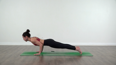 Lizette is practising yoga on a green yoga mat chaturanga
